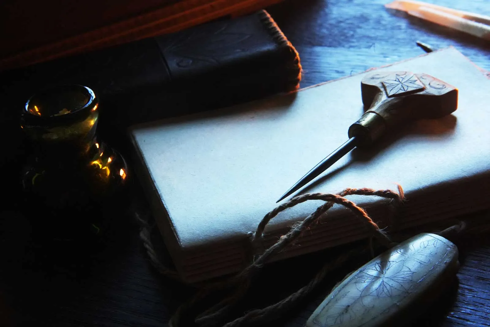 A small bound book with an awl and thread, by lamplight