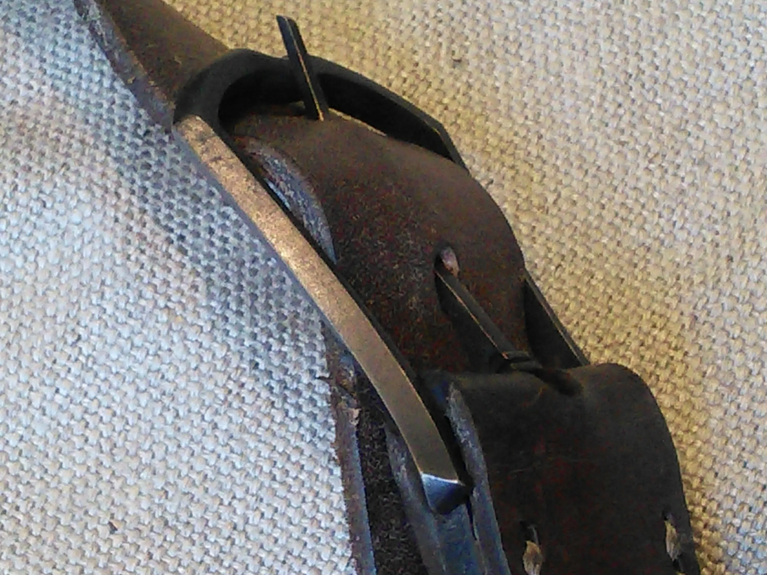 A long cast buckle on a dark leather strap, against linen